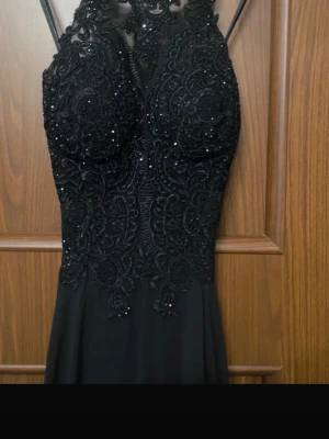 Svart långklänning med spetsdetaljer - Säljer min gamla balklänning. Så fin och elegant. Öppen i ryggen och superfina glittriga och spetsdetaljer på framsidan. Står inte storlek men passar XS-M och kupan passade mig som har B. Bra i längden för mig som är 175 cm 🖤