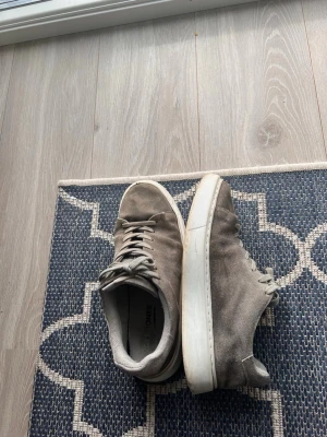 Gråa mockaskor  - Snygga sneakers i grå mocka från Jack And Jones. Storlek 41. Köpte skorna för 899kr.                             Pris kan diskuteras.