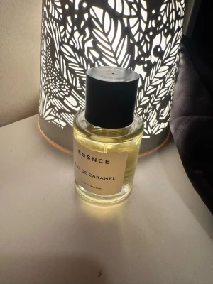 ESSNCE Eau de Caramel parfym - Säljer en ESSNCE Eau de Caramel Eau de Parfum. Flaskan är genomskinlig med en enkel vit etikett och svart lock. Doften har en söt karamellton och flaskan är i glas med rund form. Perfekt för dig som gillar gourmanddofter.
