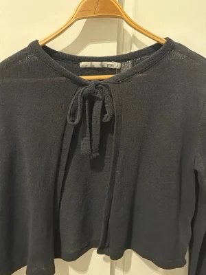 Svart stickad tröja med knytband - Svart stickad tröja från 157 med långa ärmar och knytband i halsen. Tröjan har en tunn och luftig stickning.❤️