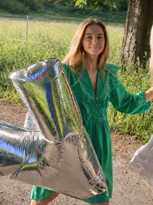 Grön klänning med volang och broderi - Snygg grön klänning med volangdetaljer och broderier upptill. Klänningen har v-ringning med knappar och långa ärmar med resår vid ärmslut. 