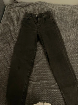 H&M Svarta raka jeans med hög midja - Säljer ett par svarta jeans med rak passform och hög midja. Klassisk femficksmodell med knapp och dragkedja framtill. Jeansen har en enkel och stilren look, perfekta till vardagsoutfits. Materialet är denim i bomull.