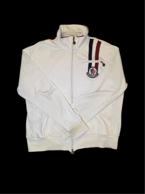 Moncler hoodie - Säljer min moncler tröja som jag köpte på Garmsmarket så jag har digitalt kvitto därifrån. Storlek XXL men den sitter som L. Mått pit to pit ca 59cm och längd ca 66cm. Skick 7/10 eftersom det är en äldre modell från moncler så finns det små spår av användning. Den är äkta och jag har digitalt kvitto från Garmsmarket. Om du har några frågor, funderingar eller vill ha fler bilder så är det bara att höra av sig.