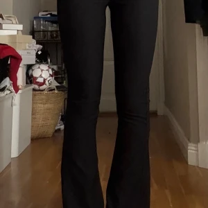 Svarta utsvängda kostymbyxor  - Säljer ett par svarta kostymbyxor med stretch och utsvängda ben och Mid midja. De är tighta upptill och har en snygg siluett som framhäver benen. Perfekta för dig som gillar en trendig och bekväm stil. Materialet är stretchigt och följsamt.