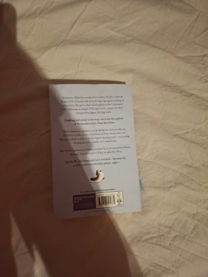 Icebreaker av Hannah Grace - Säljer boken 'Icebreaker' av Hannah Grace. Omslaget är ljusblått med illustrationer av en hockeyspelare i orange och svart UCMH-tröja samt en konståkerska i lila klänning. Perfekt för dig som gillar romantik och sport.