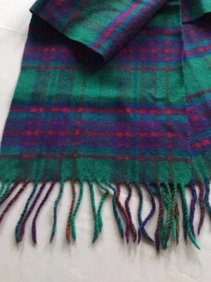 Grön-rutig halsduk med fransar - Snygg halsduk i grönt, blått och rött rutmönster. Mjuk och varm känsla, perfekt för kyliga dagar. Klassisk design med fransar i ändarna. Passar dig som gillar färg och mönster i din stil.