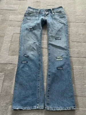 Bootuct lågmidjade jeans - Säljer ett par super coola jeans som är lowwaist och utsvängda. De har coola fickor och detalijer, slitningar som ni ser på bilderna. Det ska alltså vara så. Finns en superliten fläck på byxorna som säkert kan gå att få bort, den syns på bilderna. Finns också ett hål som syns på sista bilden, men inget som märks av alls när man bär dem. Innerbenslängd: ca 80 cm midjehöjd: ca 19-20 cm midjemått: ca 39-40 cm. IHar tyvärr ingen bild på!💕