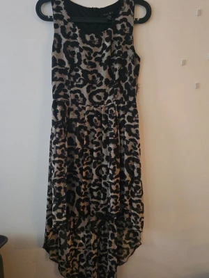 Leopardmönstrad långklänning Amisu - Säljer en snygg leopardmönstrad långklänning från Amisu. Klänningen är ärmlös och har en rund halsringning samt längre bakdel för en cool look. Perfekt för dig som vill sticka ut med ett djurmönster.                                                                     Storlek: 34 Verklig storlek: 34 Mått:  Axel-fåll: 83 cm fram.  Axel till fåll: 118 cm bak.  Midja: 66-68 cm  Axelband (Band ink.) 30 cm.  Skick: använd, har ena sidan där tyg är löst, se bilder.   SAMFRAKTAR GÄRNA!  Köp det du gilla