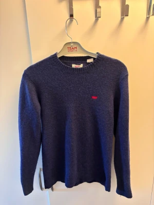 Mörkblå stickad tröja från Levi's - Snygg mörkblå stickad tröja från Levi's med rund halsringning och diskret röd logga på bröstet. Ska vara medium men har krympt, så mer som S/XS