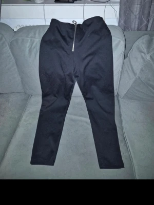 Svarta leggings Vero Moda med dragkedja  - Säljer ett par svarta leggings med hög midja och en snygg silverfärgad dragkedja framtill. De är tighta i modellen och har en enkel, stilren look som passar till det mesta. Materialet känns stretchigt och bekvämt.