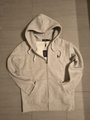 Grå Ralph Lauren hoddie  - En riktigt snygg Ralph Lauren hoddie som passar perfekt till vintern och våren aldrig använd så skicket är 10/10 priset är såklart diskuterbart Mvh Hugo 