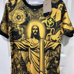 Nike Brasil CBF gul grafisk fotbollströja - Unik gul och svart Brasilien CBF fotbollströja från Nike med grafiskt tryck av Kristusstatyn och brasilianska symboler. Kortärmad modell i lätt Dri-Fit material, rund hals och svart kant vid ärmslut. Perfekt för dig som vill sticka ut på planen eller läktaren.