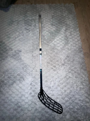 Innebandyklubba  - Säljer nu min innebandyklubba på grund av att den är för kort. Klubban är 94 kapad från 96 cm. Den är kapad där nere på grund av att jag hade lindat en ny linda innan jag insåg att den är för lång så jag kapade den där nere för att inte slösa en linda. Klubban har fått lite färgtapp från lite slag men det är inga sprickor utan bara förgtapp. .