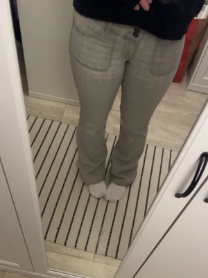 Ljusgrå bootcut jeans från Nelly - Säljer ett par ljusgrå jeans med bootcut-modell och snygga sömdetaljer. Jeansen har klassiska fickor fram och bak, samt en dekorativ knapp på bakfickan. Tillverkade i mjukt denimtyg som ger en skön passform. Köpt från Nelly för ett bra tag sen, men inte använt på väldigt länge 