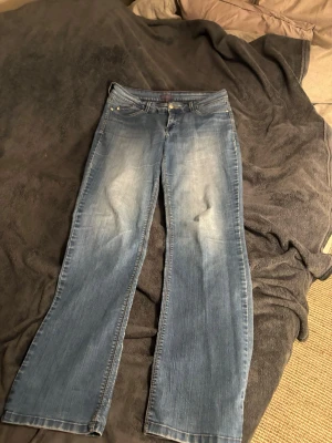 Blå bootcut jeans med slitningar !! 🩵🩵 - Säljer ett par blå bootcut jeans med snygga slitningar framtill och klassiska fem fickor. Jeansen har en något utsvängd passform nedtill och är gjorda i denim. Perfekta för dig som gillar en avslappnad men trendig stil. Storlek M/ L !! 🩵🩵Low/midwaist. KOM PRIV FÖR MÅTT!