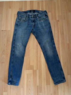 Blå jeans från replay  - Säljer ett par klassiska blå jeans från repaly Jeans med snyggt slitna detaljer och fem fickor. Jeansen har rak passform och är tillverkade i denim med en cool tvättad look. Perfekta för dig som gillar en avslappnad stil. W32 L32