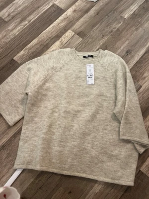 Beige oversized stickad tröja Gina Tricot - Säljer en oversized stickad tröja i mjuk beige färg från Gina Tricot. Tröjan har rund halsringning, halvlånga ärmar och en avslappnad passform. Perfekt för lager på lager och enkel att styla till olika looks.