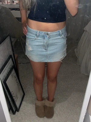 lågmidjad jeanskjol - Cool ljusblå jeanskjol med slitna detaljer och rå kant. Kjolen har klassiska fickor fram och bak, bälteshällor och knappstängning. Perfekt för dig som gillar en avslappnad och trendig look. midjemått 34-35cm och längd på kjolen 26cm ❤️