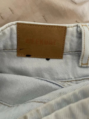 Ljusblå Weekday Rowe jeans - Säljer ett par ljusblå jeans från Weekday, modellen Rowe. Jeansen har klassisk femficksdesign, raka ben och är tillverkade i denim med synliga kontrastsömmar. Perfekta för en avslappnad och trendig look. Den är dock ljusare vid låren av nått slag av fläck. 