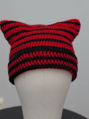 Crochet cat beanie virkad kattmössa röd svart randig - Helt ny virkad mössa med kattöron. Onesize, passar upp till ca 59cm. Virkad i mjukt akrylgarn. Färger kan variera beroende på skärminställningar.