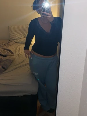 Hoodrich Blåa mjukisbyxor med tryck - Säljer ett par ljusblå mjukisbyxor med avslappnad passform och resår i midjan. Byxorna har ett vitt tryck på ena benet och är perfekta för en chill och bekväm stil. Materialet känns mjukt och skönt mot huden.