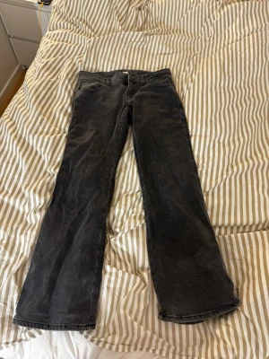 svarta y2k jeans - Svarta y2k jeans från Gina Tricot i bootcut med medelhög midja. Jeansen har två knappar och dragkedja fram, klassiska fem fickor samt bakfickor med lock och knapp. Storlek 40 nypris ca 500 kr och är knappt använda!