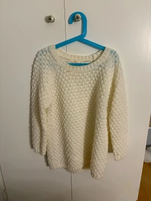 Vit stickad tröja med strukturmönster - Mysig vit stickad tröja med rund hals och ett snyggt strukturmönster över hela plagget. Tröjan har trekvarts ärmar. 