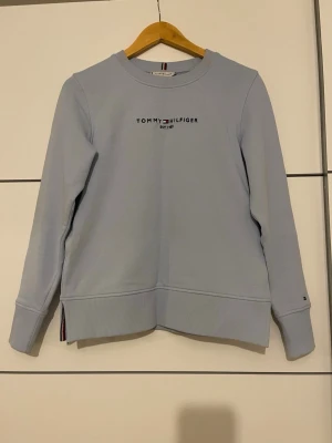 Tommy Hilfiger tröja - Fin tommy tröja i ljusblå, använd en gång så i väldigt bra skick, i princip ny. Den är xss men passar även xs/s  Djur/rökfri hem