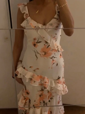 Vit långklänning med volanger och blommor - Aldrig använd, skriv privat för fler bilder🩷 Klänningen säljs inte längre.