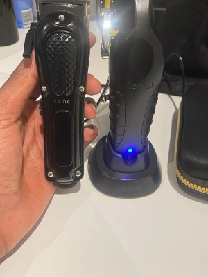Kemei hårtrimmer set svart - OBV BARA DEN ÅT VÄNSTER. Snyggt hårtrimmer set från Kemei i svart med metall- och plastdetaljer. Ergonomiskt grepp och laddningsstation med blå LED-indikator. Perfekt för styling och trimning av hår och skägg. Medföljer praktisk förvaringsväska med dragkedja.