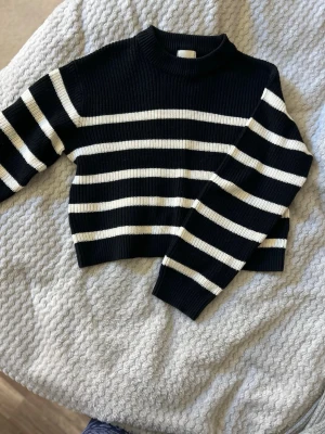 Svartvit randig stickad tröja - Säljer en svart stickad tröja från HM, väldigt varm och skön. Är i XS men passar som en S med.