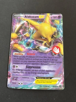 Pokémonkort M Alakazam EX - Säljer ett Pokémonkort av typen M Alakazam EX med holografisk yta. Kortet har färgstarka lila, gula och rosa detaljer och är nummer 25/124. Perfekt för samlare eller Pokémonfans.