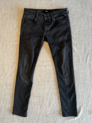Svarta replay hyperflex - Säljer ett par svarta skinny jeans från Replay med klassisk femficksmodell och låg midja. Jeansen har stretchigt material för skön passform och diskreta sömmar. Perfekta för dig som gillar en smal siluett och tidlös stil.