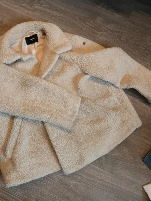 Beige teddyjacka från Bik Bok - Supermjuk och fluffig teddyjacka från Bik Bok i creme färg. Jackan har bred krage, sidofickor. Knapparna är borttagna och finns en fläck på armen som går bort i tvätten 🥰jackan är storlek L men har användts på mig som är xs-s för att sitta oversized