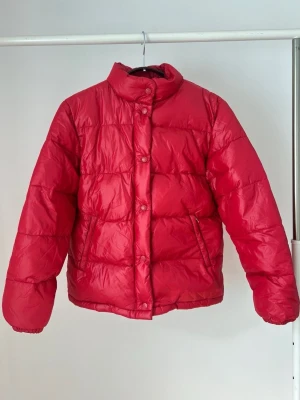 Jacka ❤️ - Röd dunjacka från Amica. Jackan har en hög krage och stängs med knappar. Den har även fickor på sidorna. Storlek 36 ❤️