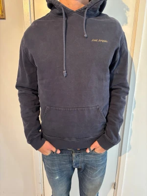 Axel Arigato hoodie   - Snygg mörkblå hoodie från Axel Arigato med broderad logga på bröstet. Klassisk känguruficka framtill, justerbar huva med dragsko och ribbade muddar. Perfekt för en chill och stilren look. Tillverkad i mjukt bomullsmaterial.