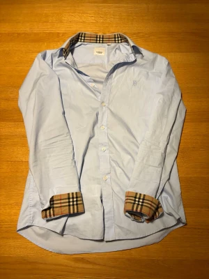 Burberry skjorta  - As snygg sällsynt burberry skjorta i baby blue! Den är i mycket bra skick förutom några fläckar som säkert går  bort i tvätten! Fört till kvarn! 