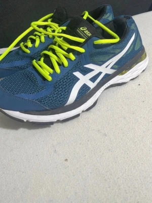 Asics sneakers - Snygga blåa sneakers från Asics med vit logga på sidan och neongula skosnörens. Ovandelen är i mesh och syntetmaterial för bra andningsförmåga. Sulan är vit med svarta och grå detaljer. Perfekta för dig som gillar sportig stil.