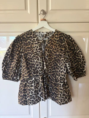 Leopardmönstrad blus med puffärm - Snygg blus med leopardmönster och puffiga trekvartsärmar. Blusen har knytning framtill och en lätt utställd passform som ger en trendig siluett. Tillverkad i ett glansigt tyg som känns lyxigt och skönt mot huden.