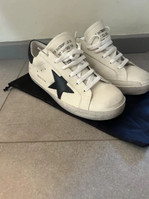Vita golden goose skor med svart stjärna  - Snygga vita golden goose skor perfekt till sommaren, har andvänt dessa 1 gång men vill sälja pga dem är för små har storlek 41,5 men dessa är pytte lite för små 