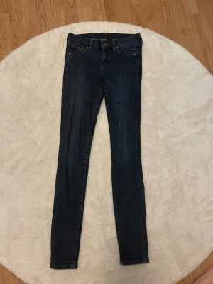 Mörkblå skinny jeans - Säljer ett par mörkblå skinny jeans med klassisk femficksdesign och smal passform. Jeansen har normal midja, dragkedja och knapp framtill samt två bakfickor. Perfekta till en avslappnad stil och passar till det mesta.