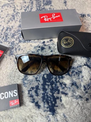 Ray-Ban bruna solglasögon wayfarer - Säljer ett par klassiska Ray-Ban Wayfarer solglasögon i brunmelerad färg. Snygg, tidlös design med mörka glas och robust båge. Kommer med originalfodral och box. Perfekta för soliga dagar och ger en cool vibe till din outfit. Kan gå ner i pris vid snabb affär