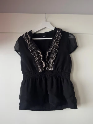 Svart blus med volang från H&M - Storlek M, bra skick