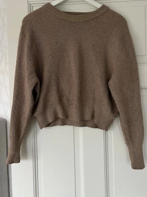 Brun ribbstickad tröja - Mysig brun ribbstickad tröja med avslappnad passform och rund halsringning. Tröjan har långa ärmar och breda muddar vid ärmslut och nederkant. Perfekt för lager på lager under kyliga dagar. Som ni kan se på bilden är den nopprig längst ner men inget som märks i helheten.