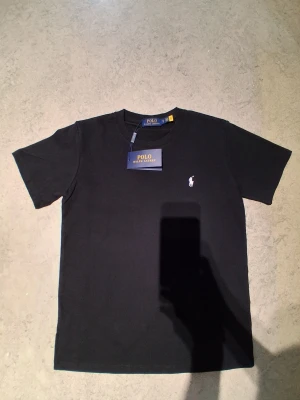 Polo Ralph Lauren T-shirt  - Helt ny polo Ralph Lauren T-shirt svart med vit märke för endast 399kr jättebra kvalitet med lapen. Har ni funderingar eller är intresserad skriv till mig.