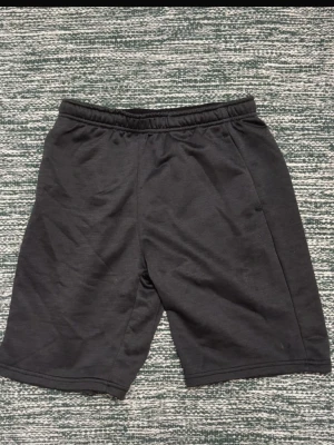 Svarta shorts från SOC - Svarta shorts från SOC med elastisk midja och enkel, stilren design. Perfekta för träning eller chill dagar. Tillverkade i mjukt material som känns skönt mot huden. De är lite noppriga. I storlek 170.