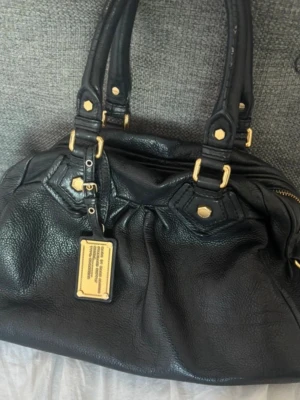 svart marc jacobs väska - svart marc jacobs väska, lite slitning vid handtagen och färgen har gått bort lite på metallen under väskan, annars bra kvalitet💕 Skriv vid frågor. lämna gärna prisförslag!  Bredd:35 cm höjd:19 cm