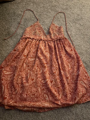Zara kläning  - Super söt orange mönstrad Zara kläning. Säljer då jag inte använder den. V formad där uppe och djup i ryggen med snörning. Inte använd och därför nytt skick. Skulle säga storleken är runt S-M men passar nog från XS-M. Pris 250 just nu, kan diskuteras. Hör av er för intresse!🧡🩷