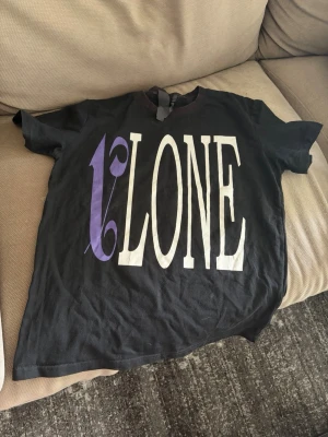 Svart VLONE x Palm Angels t-shirt - Säljer en svart t-shirt med stort vitt och lila VLONE-tryck på framsidan och Palm Angels-tryck i vitt och lila på baksidan. 