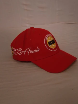 Mitchell & Ness keps - Snygg röd keps Justerbar passform och böjd skärm. Perfekt för basketfans. Houston Rockets NBA finals tryck. Oanvänd